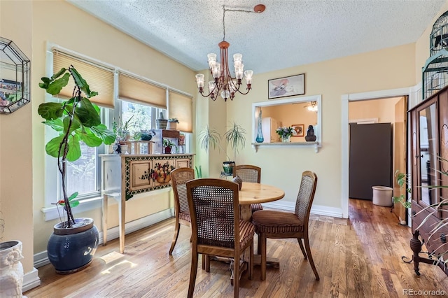 1559 Elm St, Denver, CO 80220 - dining area with a chandelier, wood finished floors, a textured ceiling, and baseboards