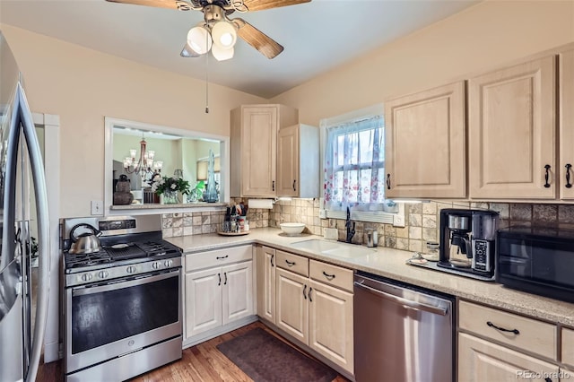 1559 Elm St, Denver, CO 80220 - kitchen featuring stainless steel appliances, a sink, tasteful backsplash, ceiling fan, and light wood-type flooring