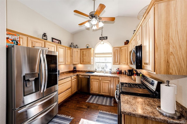 kitchen with vaulted ceiling, appliances with stainless steel finishes, sink, dark stone countertops, and dark wood-type flooring