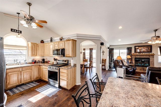 kitchen with a tile fireplace, appliances with stainless steel finishes, light brown cabinets, and ceiling fan