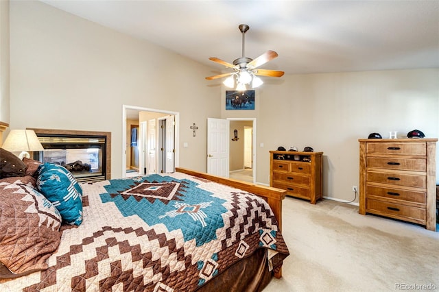 bedroom with light colored carpet, a tile fireplace, ceiling fan, and a high ceiling