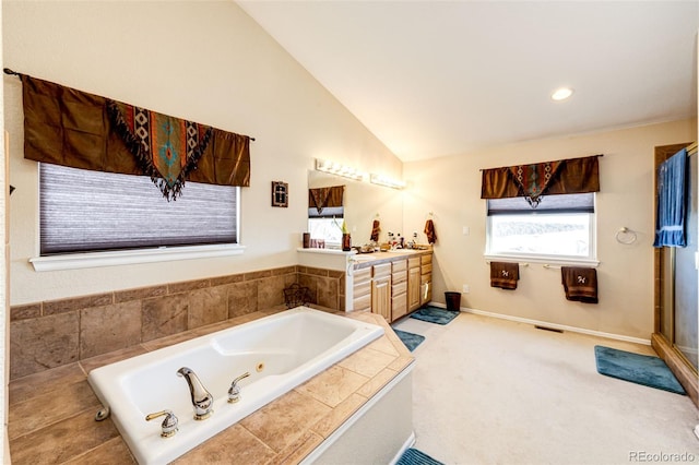 bathroom with lofted ceiling, vanity, and a relaxing tiled tub