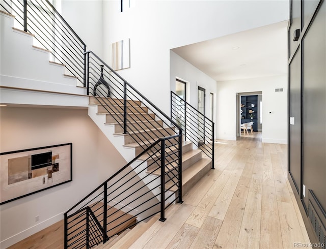 stairs with a towering ceiling and hardwood / wood-style floors