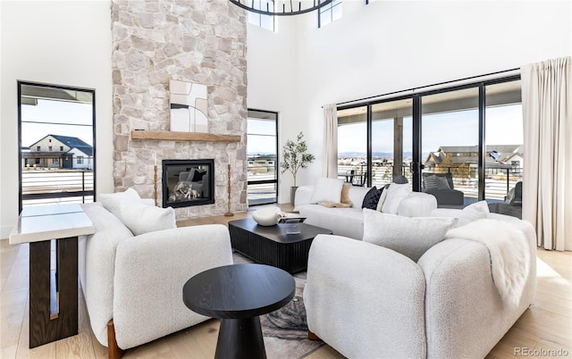 living room with light hardwood / wood-style floors, a stone fireplace, and a healthy amount of sunlight