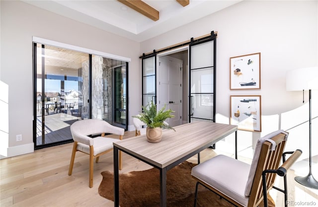 dining room with light hardwood / wood-style floors, a barn door, and beamed ceiling