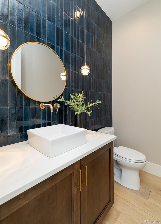 bathroom with tile walls, toilet, vanity, and hardwood / wood-style floors