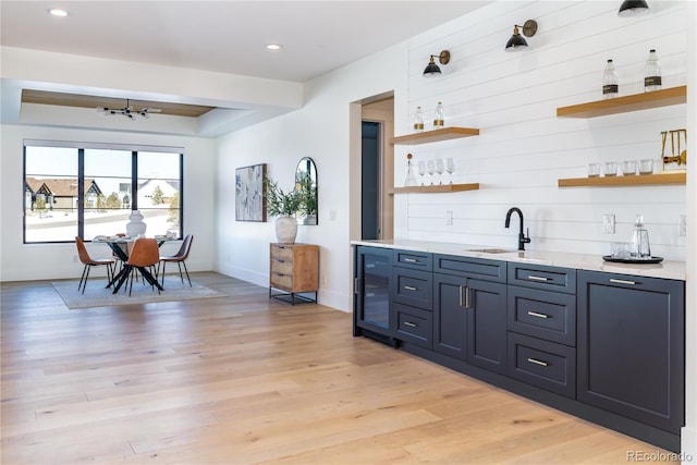 bar with sink, light hardwood / wood-style flooring, blue cabinetry, and wine cooler