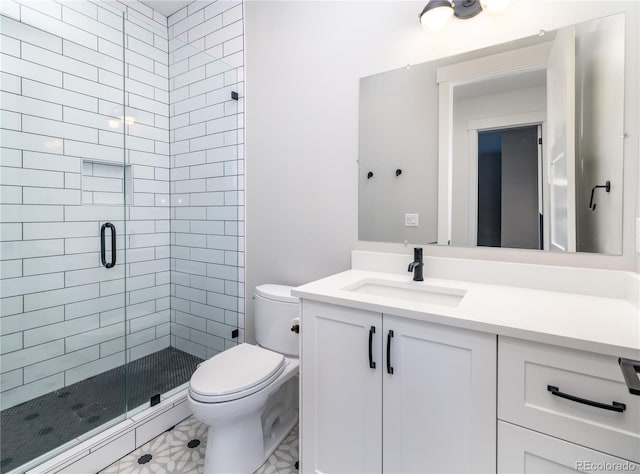 bathroom featuring toilet, a shower with shower door, and vanity