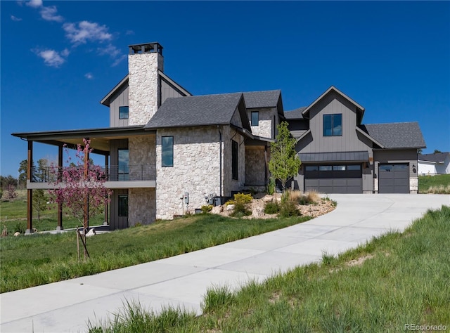 2442 Fox View Trl, Franktown, CO 80116 - view of front of house featuring stone siding, a front yard, concrete driveway, a garage, and board and batten siding