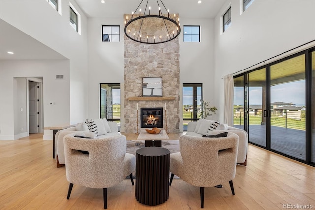 2442 Fox View Trl, Franktown, CO 80116 - living area with a high ceiling, light wood-type flooring, a chandelier, and a stone fireplace