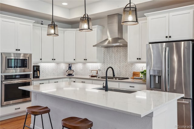 10165 E 59th Ave, Denver, CO 80238 - kitchen featuring wall chimney range hood, decorative backsplash, a breakfast bar, and stainless steel appliances