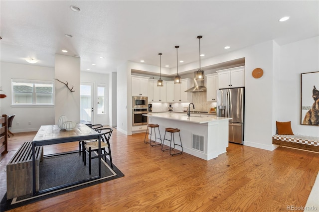 10165 E 59th Ave, Denver, CO 80238 - kitchen with visible vents, white cabinets, appliances with stainless steel finishes, and wall chimney exhaust hood