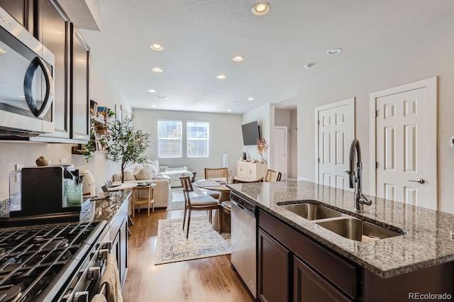 kitchen featuring sink, dark hardwood / wood-style floors, light stone countertops, an island with sink, and stainless steel appliances