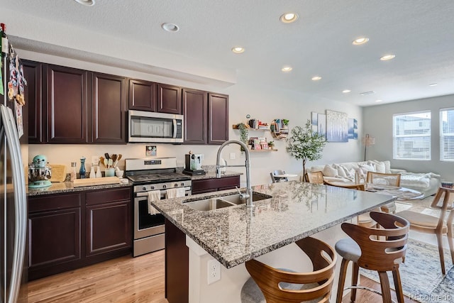 kitchen featuring a breakfast bar, sink, light wood-type flooring, an island with sink, and stainless steel appliances