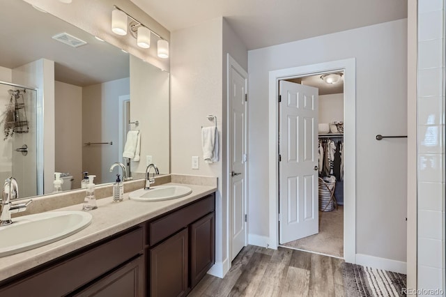 bathroom featuring wood-type flooring, vanity, and a shower with shower door