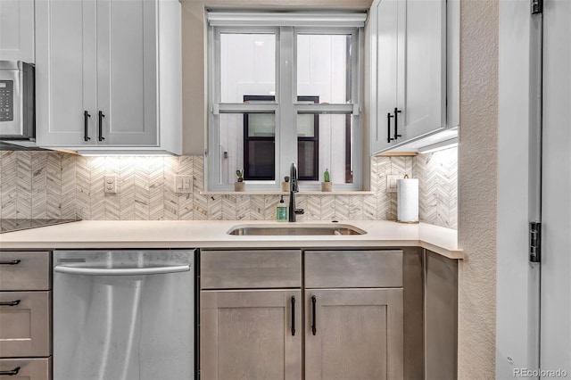 kitchen featuring stainless steel appliances, light countertops, a sink, and backsplash