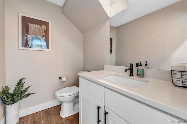 bathroom featuring baseboards, toilet, wood finished floors, vaulted ceiling, and vanity