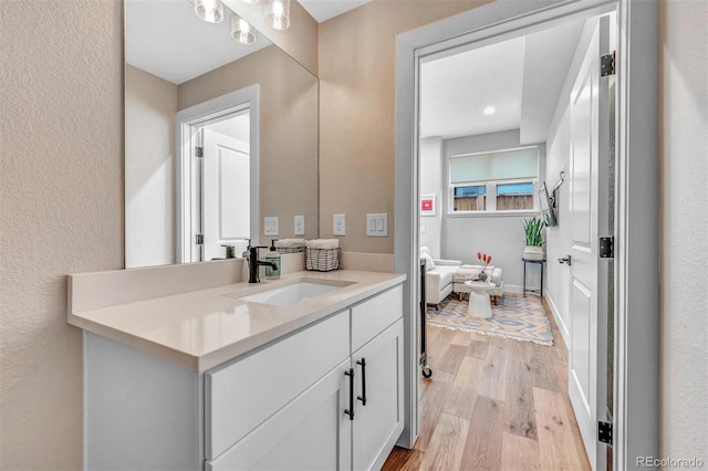 bathroom featuring a textured wall, wood finished floors, vanity, and baseboards