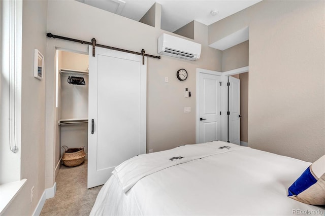 bedroom featuring a barn door, a wall unit AC, light colored carpet, a spacious closet, and a closet