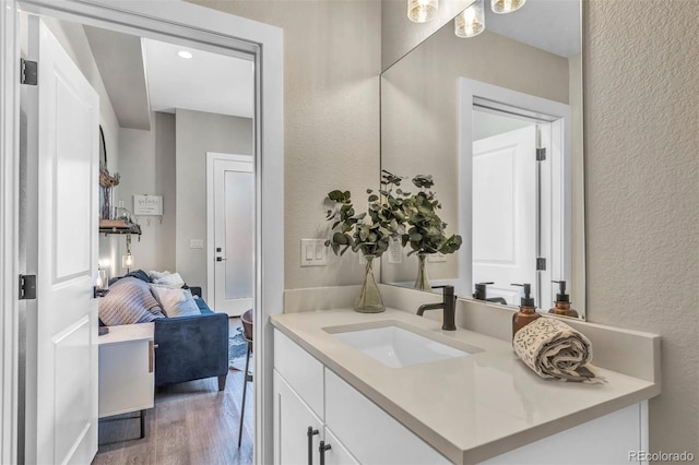 ensuite bathroom with vanity, ensuite bathroom, wood finished floors, and a textured wall