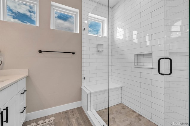 bathroom with wood finished floors, a shower stall, vanity, and baseboards