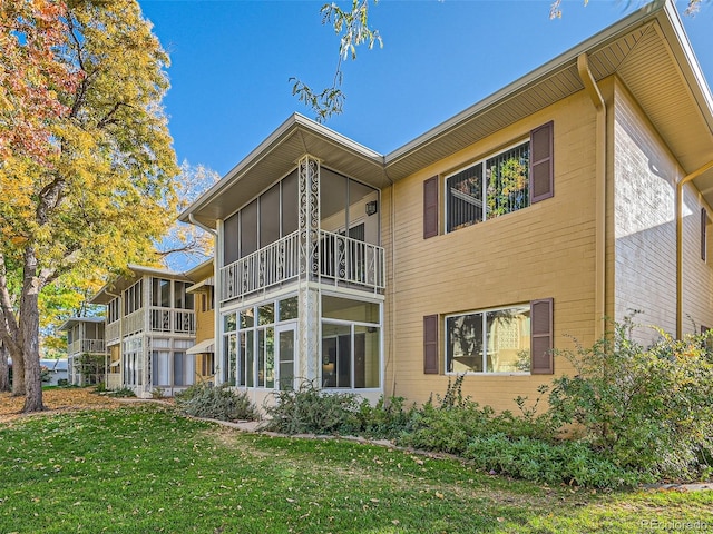 rear view of property with a balcony and a lawn