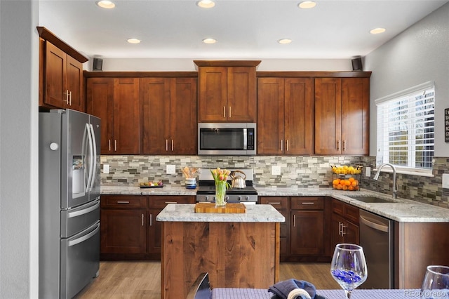 6464 Elsinore Dr, Colorado Springs, CO 80923 - kitchen featuring light wood-style floors, appliances with stainless steel finishes, light stone counters, a sink, and decorative backsplash
