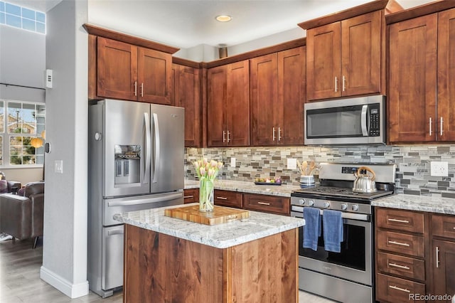 6464 Elsinore Dr, Colorado Springs, CO 80923 - kitchen with backsplash, a kitchen island, light stone counters, and stainless steel appliances