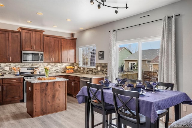 6464 Elsinore Dr, Colorado Springs, CO 80923 - kitchen with light wood-style floors, a center island, a sink, stainless steel appliances, and decorative backsplash