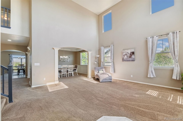 42311 Forest Oaks Dr, Elizabeth, CO 80107 - living area featuring arched walkways, a chandelier, high vaulted ceiling, ornate columns, and carpet