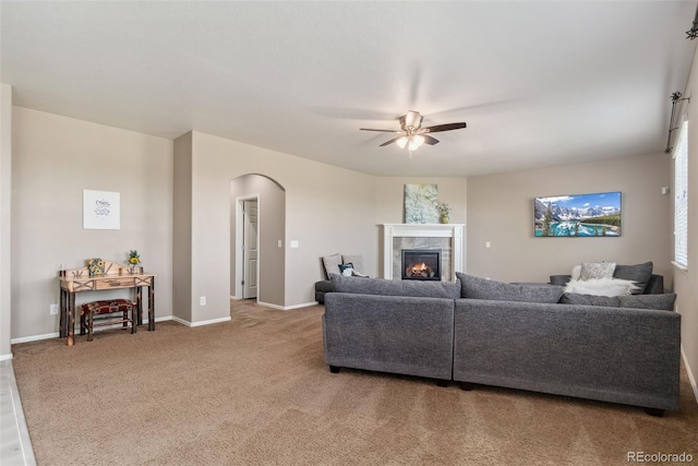 42311 Forest Oaks Dr, Elizabeth, CO 80107 - living area with arched walkways, ceiling fan, a tiled fireplace, carpet flooring, and baseboards