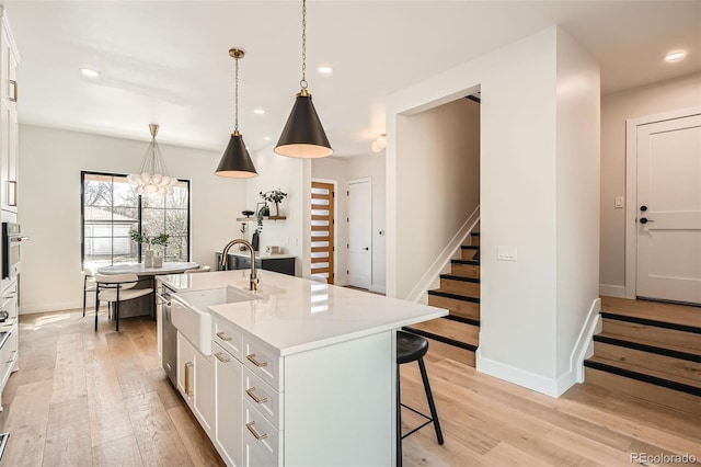 3649 W 21st Ave, Denver, CO 80211 - kitchen featuring light wood-type flooring, a breakfast bar, white cabinetry, a sink, and recessed lighting