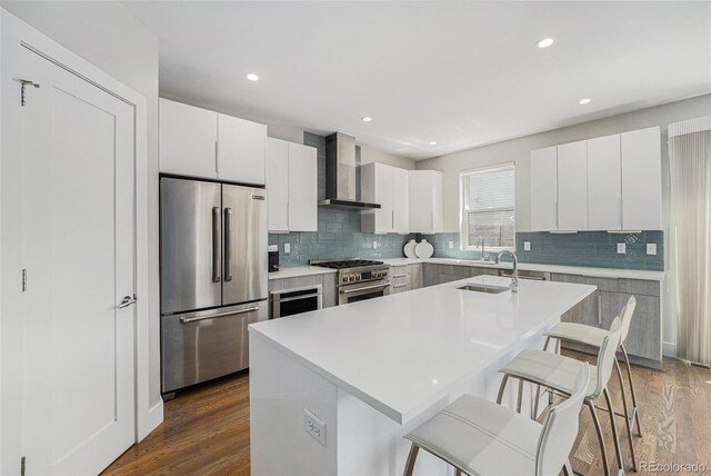 4102 Quivas St, Denver, CO 80211 - kitchen featuring high end appliances, wall chimney range hood, a breakfast bar area, backsplash, and dark wood-type flooring