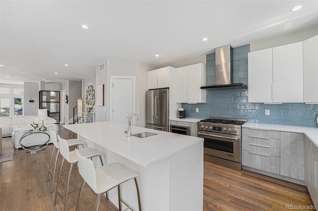 4102 Quivas St, Denver, CO 80211 - kitchen with wall chimney exhaust hood, high quality appliances, a breakfast bar, wood finished floors, and modern cabinets