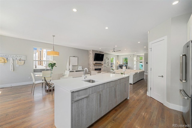 4102 Quivas St, Denver, CO 80211 - kitchen with high quality fridge, dark wood-style floors, a large fireplace, a kitchen island with sink, and ceiling fan