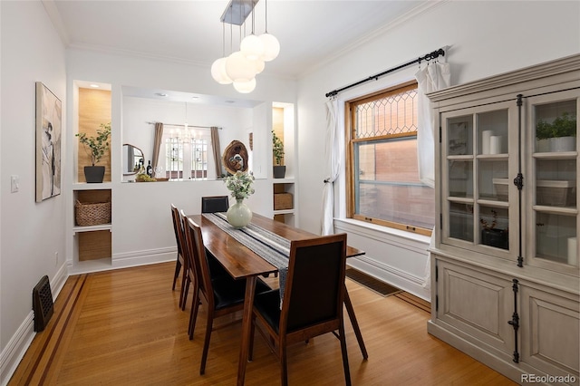 dining room with an inviting chandelier, baseboards, ornamental molding, and light wood finished floors