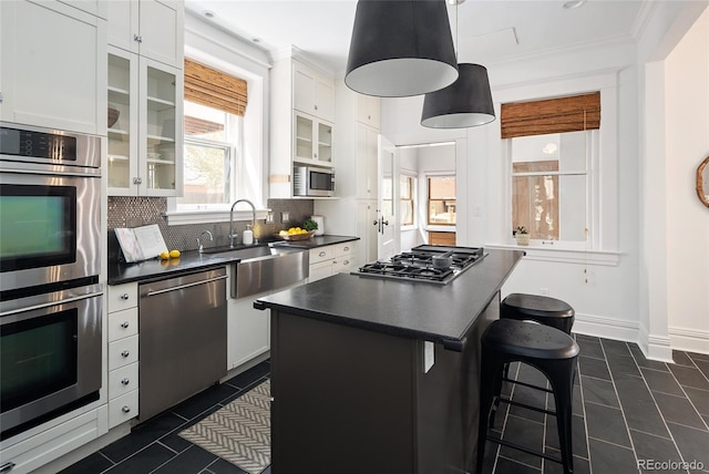 kitchen featuring a sink, appliances with stainless steel finishes, dark countertops, and dark tile patterned floors