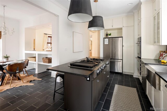kitchen featuring dark countertops, stainless steel appliances, white cabinetry, a kitchen island, and dark tile patterned floors
