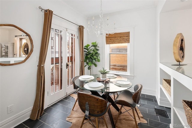 dining space with an inviting chandelier, dark tile patterned floors, baseboards, and visible vents