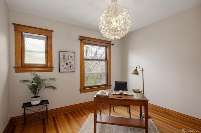 office space featuring baseboards, an inviting chandelier, and wood finished floors