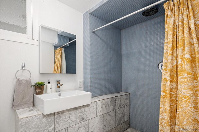 bathroom featuring a tile shower and a sink