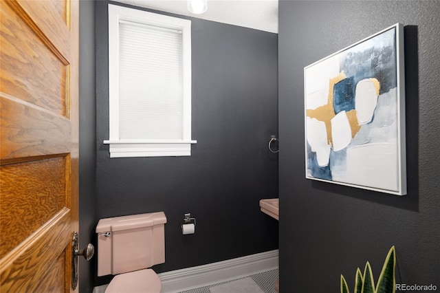 bathroom with toilet and baseboards