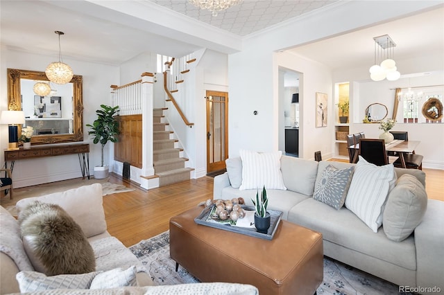 living area featuring crown molding, wood finished floors, baseboards, stairway, and a notable chandelier