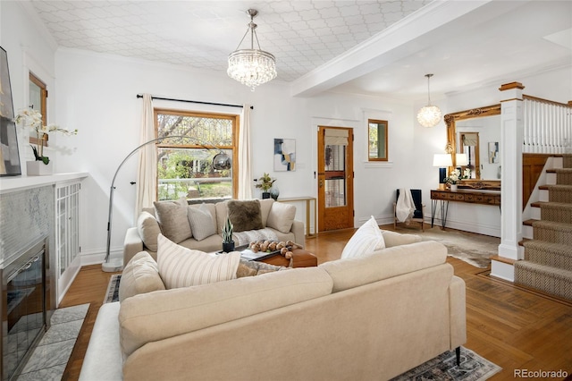 living area with ornamental molding, stairs, wood finished floors, and a chandelier