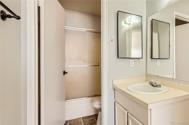 full bathroom with tile patterned floors, vanity, toilet, and bath / shower combo with glass door