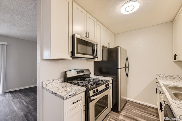10712 E Exposition Ave Unit 209, Aurora, CO 80012 - kitchen featuring stainless steel appliances, a textured ceiling, baseboards, light countertops, and wood finished floors