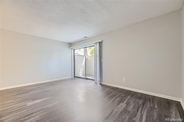 spare room featuring a textured ceiling and dark wood-type flooring