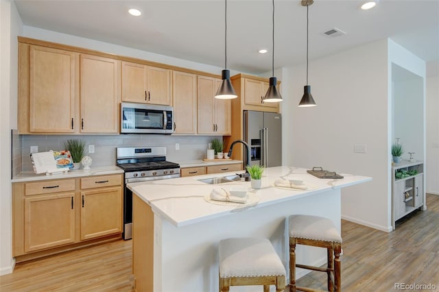 2463 Alpine St, Longmont, CO 80504 - kitchen featuring stainless steel appliances, light wood-style flooring, light brown cabinetry, an island with sink, and recessed lighting