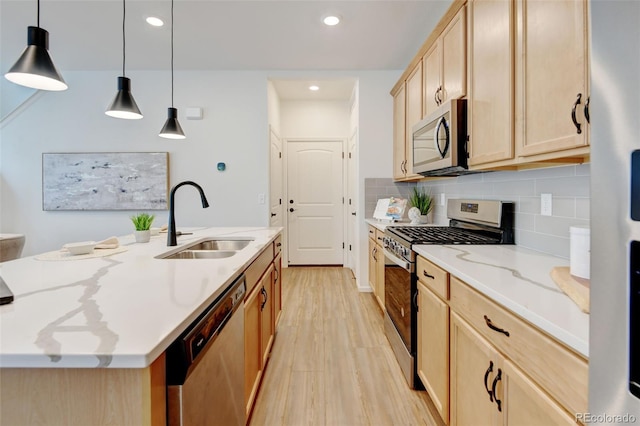 2463 Alpine St, Longmont, CO 80504 - kitchen with stainless steel appliances, light wood-style floors, light brown cabinetry, a center island with sink, and backsplash
