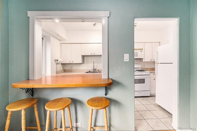 665 Washington St Unit 5B, Denver, CO 80203 - kitchen featuring white appliances, white cabinetry, a kitchen bar, light tile patterned floors, and light countertops